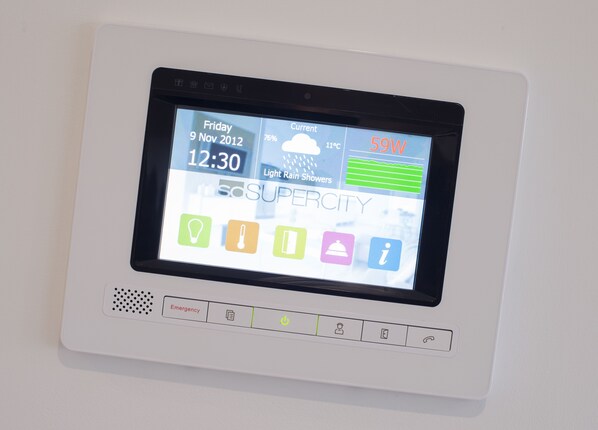 Una pantalla digital que muestra un pronóstico del tiempo, botones de emergencia e iconos para diversos servicios del hotel.