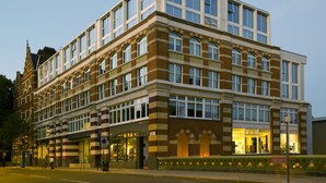 A multi-story hotel with a brick facade, large windows, and a ground-level entrance.