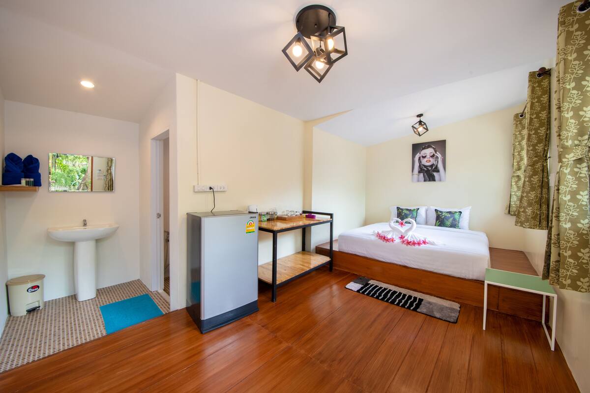 A bedroom with a bed, a desk, a sink, and a mirror.