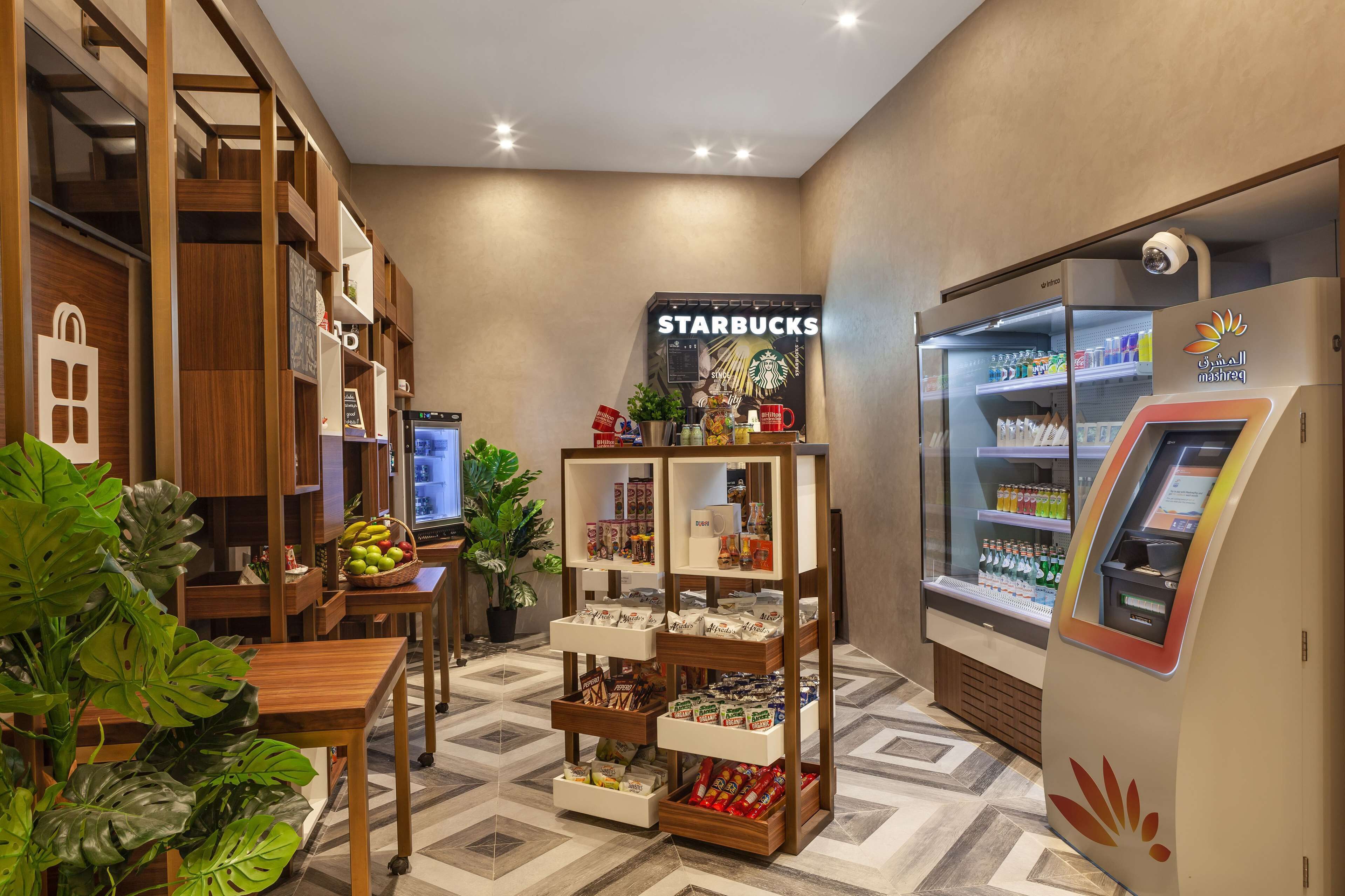 A Starbucks inside a mall with a self-service kiosk and a display of snacks and drinks.