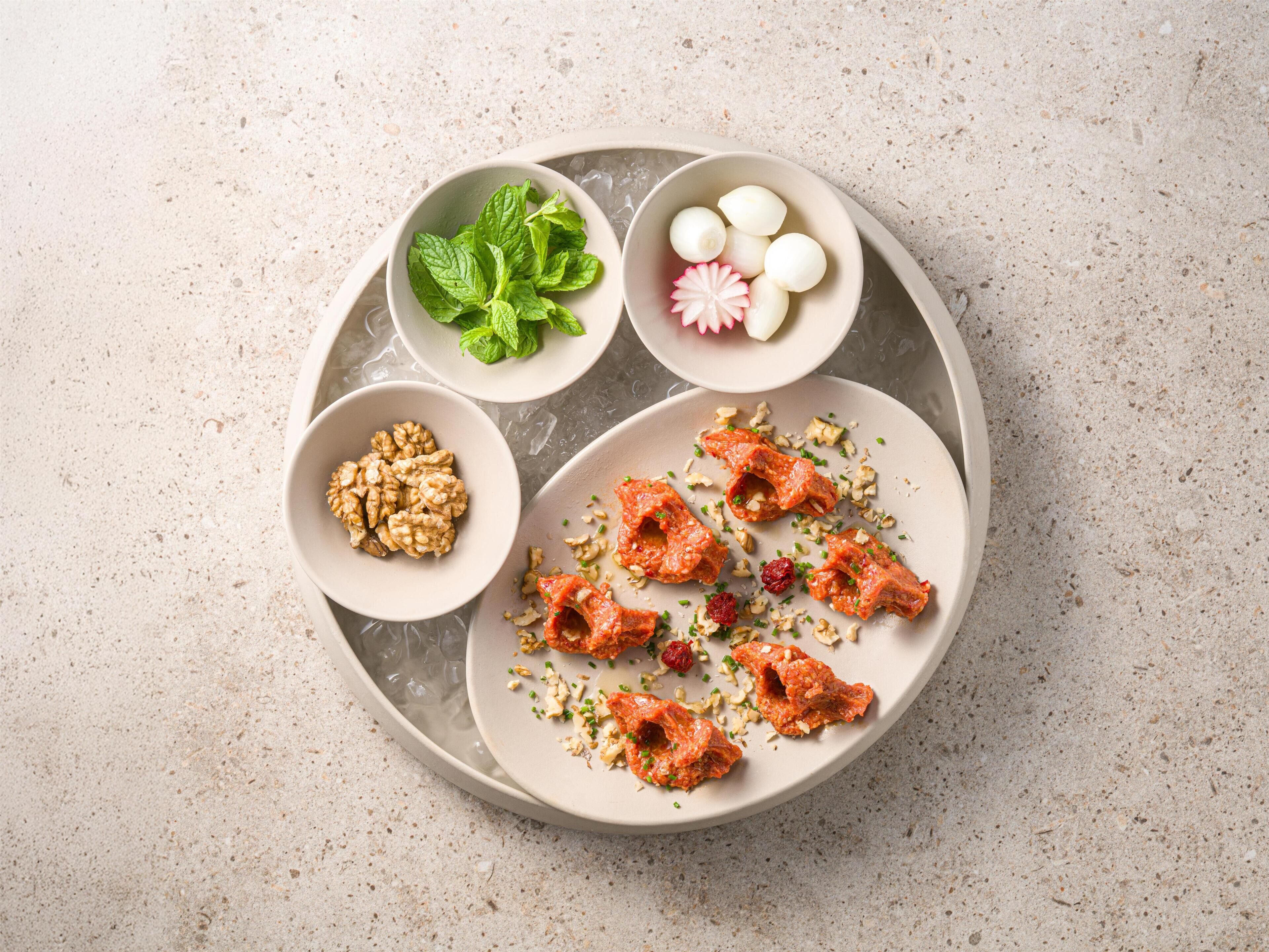 A plate with food items, including nuts, a mint leaf, and a decorative item.