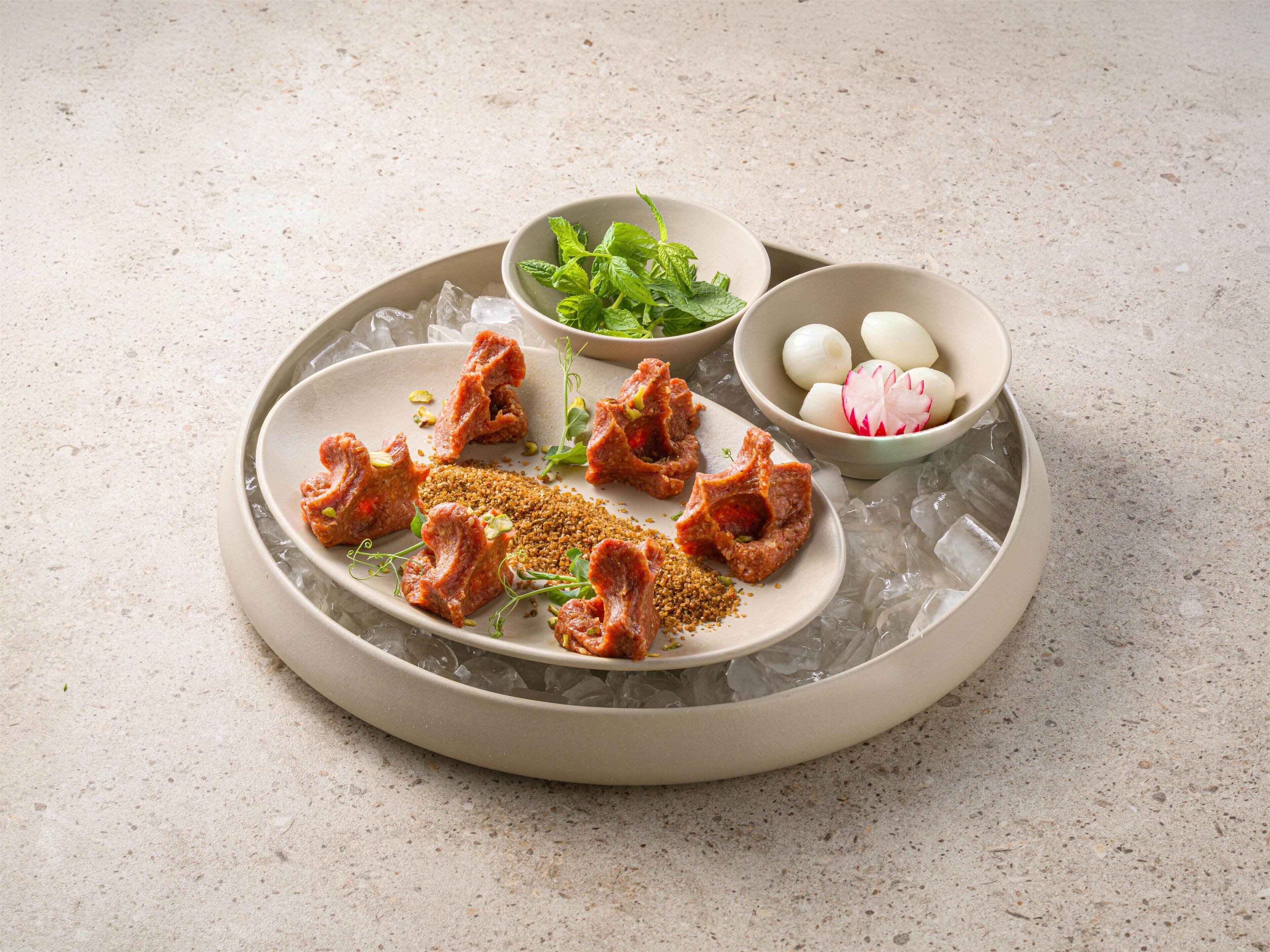 A plate with food items, ice, and bowls of greens and radishes.