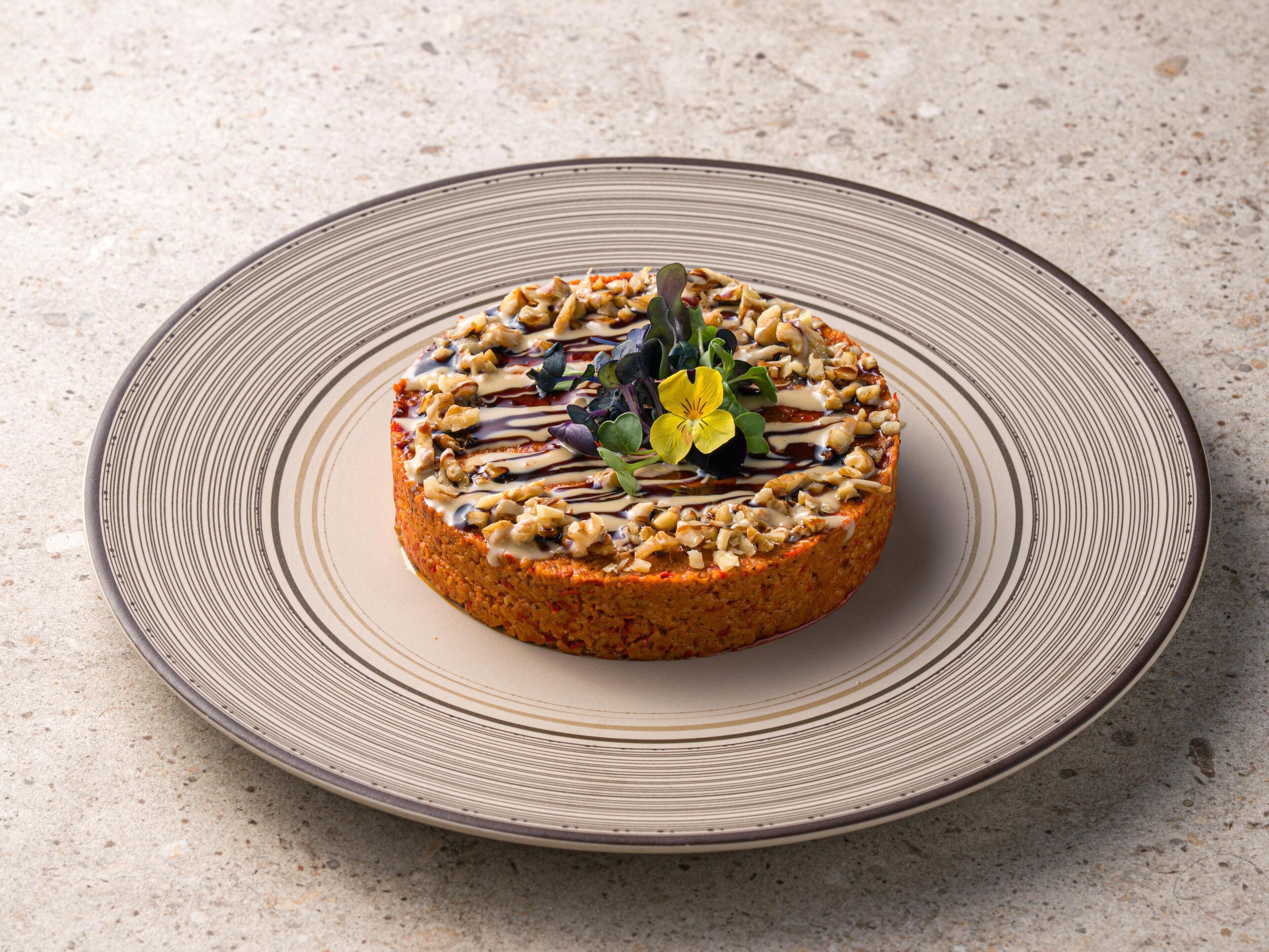 A round plate with a textured design, placed on a speckled surface.