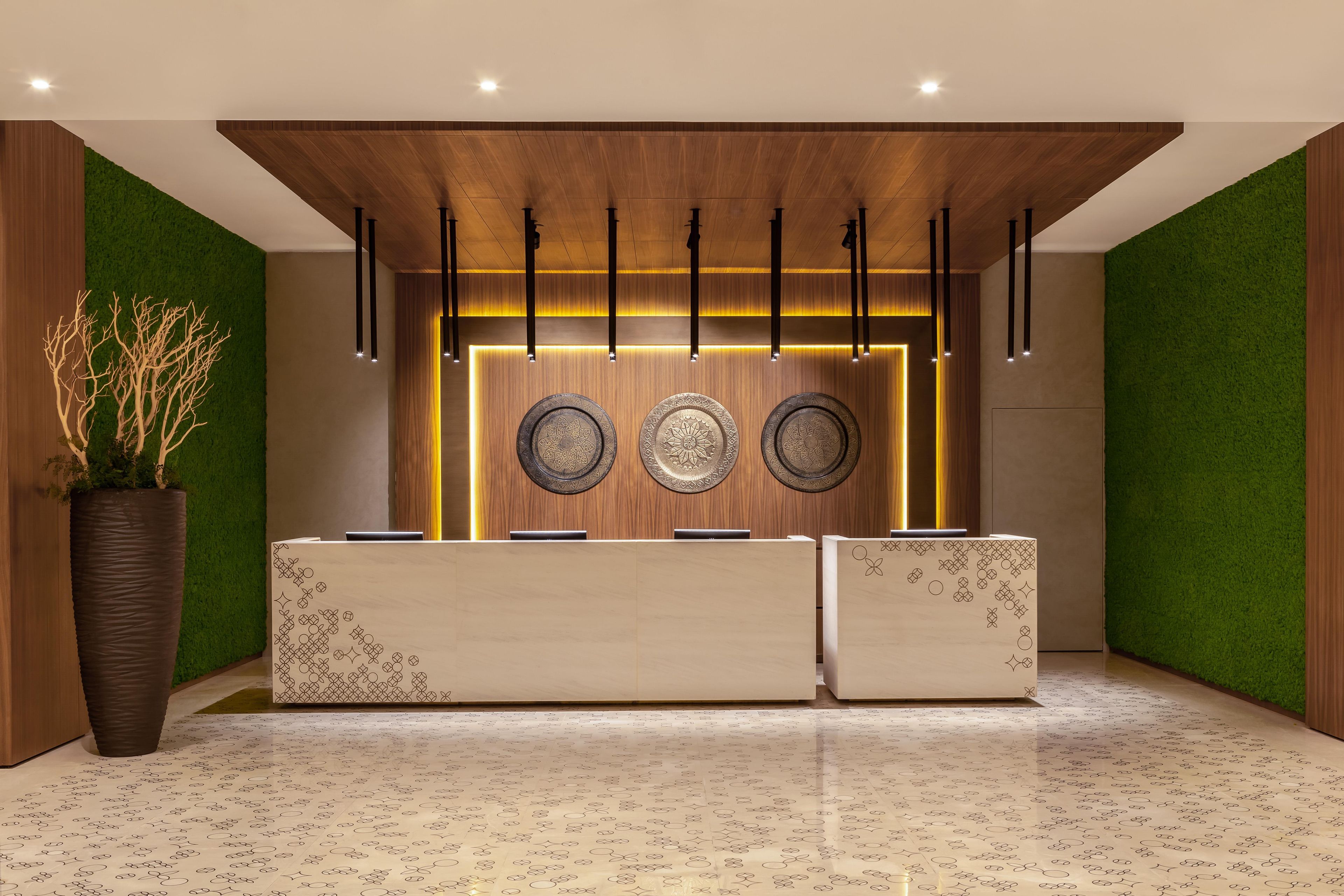 A reception desk with a wooden finish, a green wall, and a patterned floor.