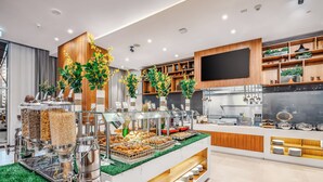 En moderne morgenmadsbuffet med et udvalg af mad, en kaffestation og dekorative planter.