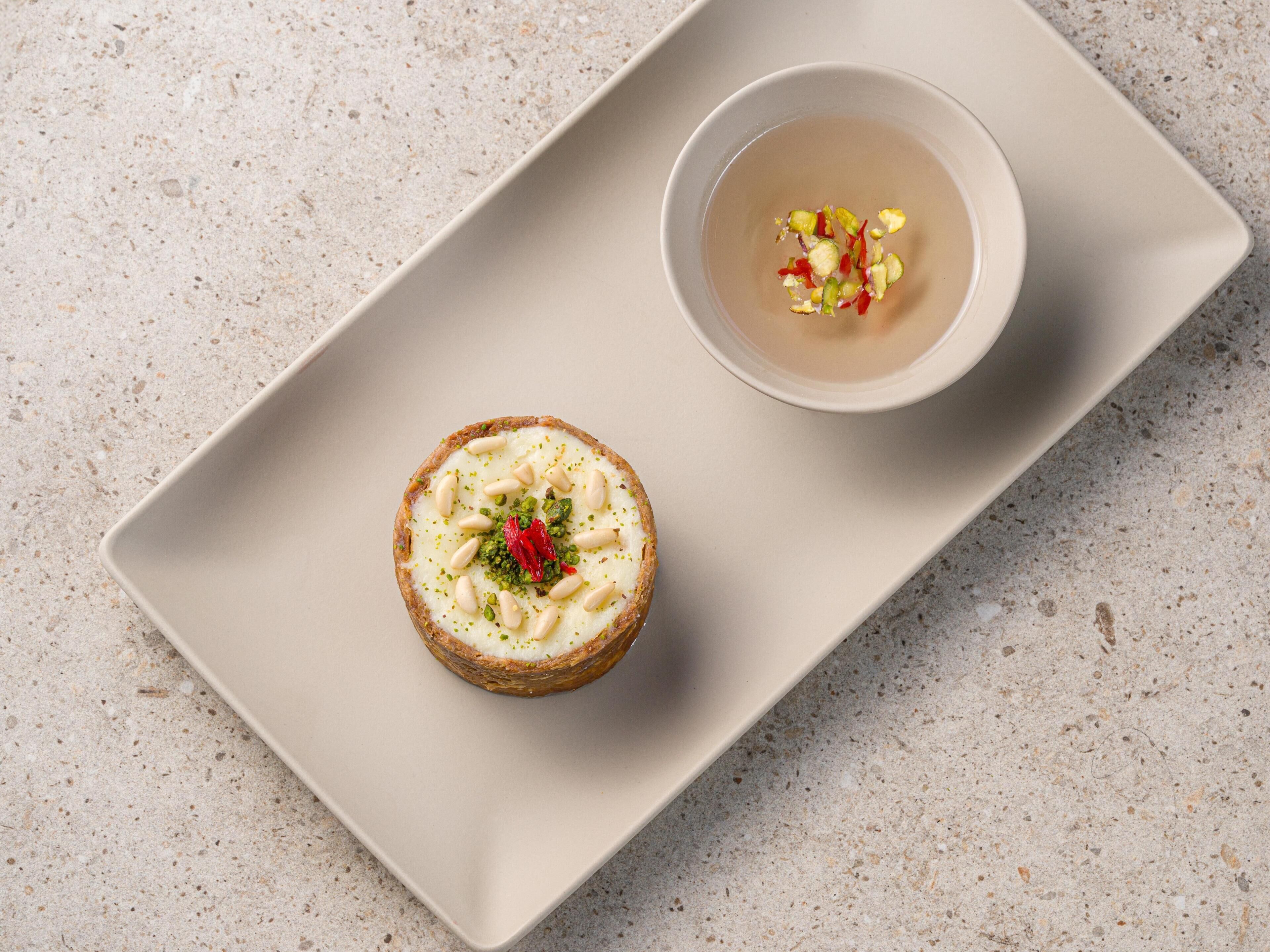 Un dessert servi sur une assiette rectangulaire, accompagné d’un petit ramequin de sauce.