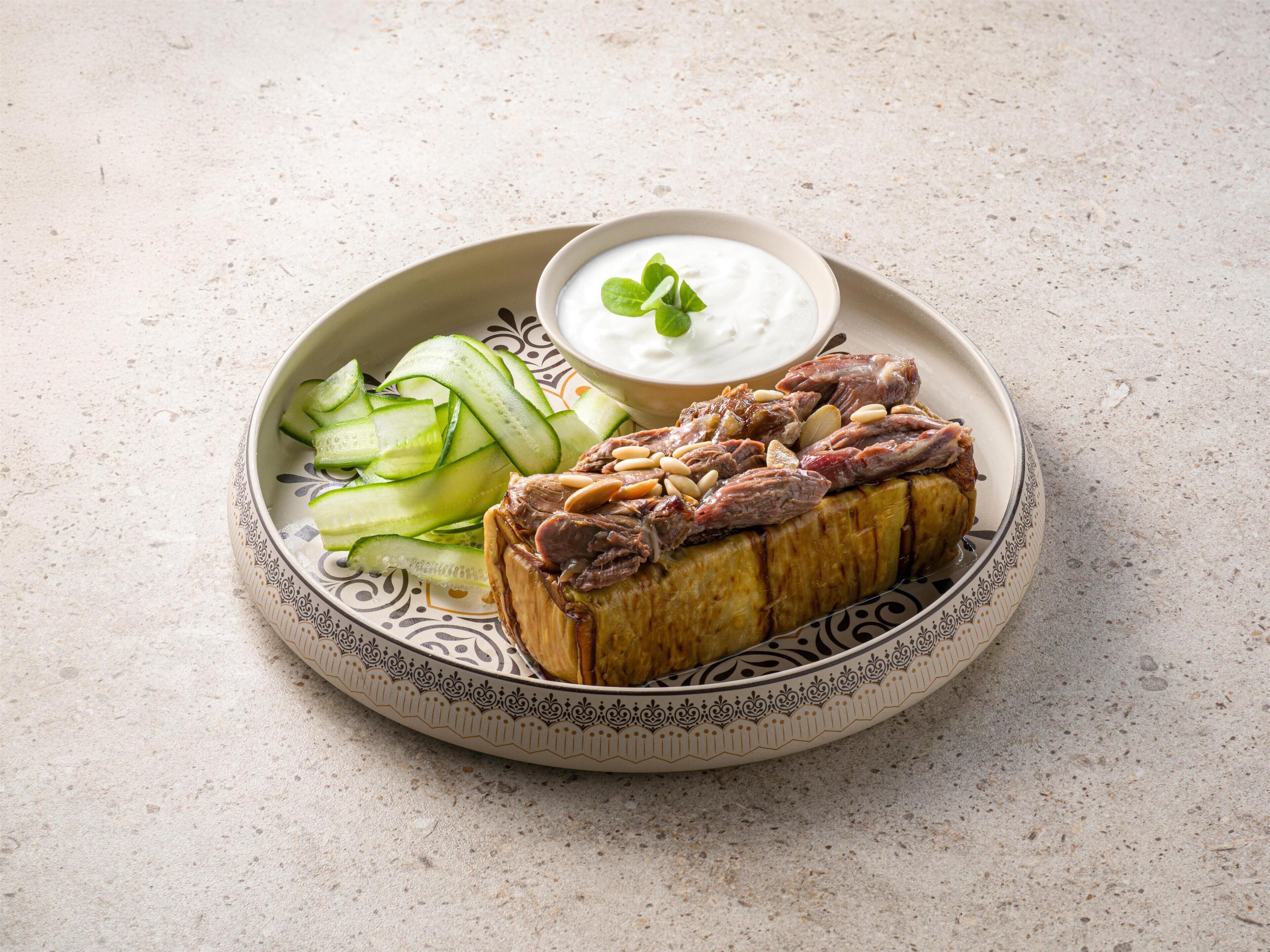 Ein Teller mit Brot, belegt mit Fleisch und Nüssen, eine Schüssel Joghurt und Gurkenscheiben.