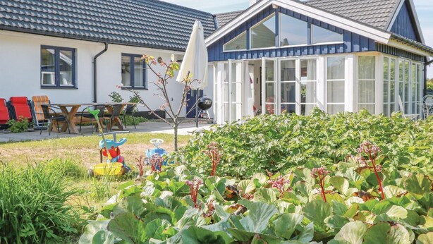 Ein Haus mit Wintergarten, ein Garten mit Wasserpflanzen und Gartenmöbeln.