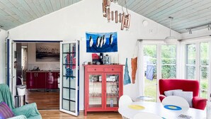 Ein geräumiger Wohnbereich mit einem roten Schrank, einem weißen Esstisch mit bunten Tischsets und einem roten Sessel.