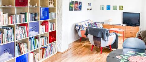 A cozy living room with a bookshelf, a sofa, a TV, and a small table.