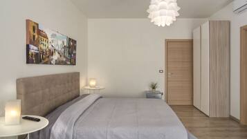 A bedroom with a bed, bedside table, lamp, and a painting on the wall.