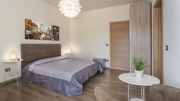 Camera da letto moderna con un letto grande, comodini, un tavolino con una pianta e una porta in legno.