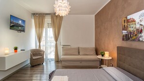 A modern hotel room with a bed, a sofa, a chair, a desk, and a painting on the wall. - La Candelaria (Pisa)