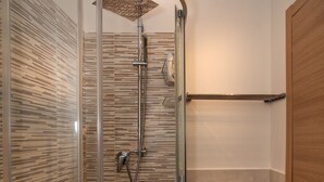 A glass-enclosed shower with a wooden panel wall, a towel rack, and a wooden door. - La Candelaria (Pisa)