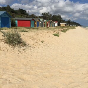 Uma praia com uma fileira de cabanas coloridas.