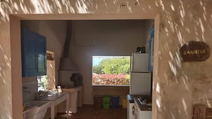 A compact kitchen with a gas stove, a built-in oven, and a window overlooking a garden. - Casale Imperatore (Ragusa)