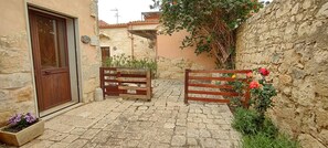 A stone courtyard with a wooden gate, a door, and potted plants. - Casale Imperatore (Ragusa)
