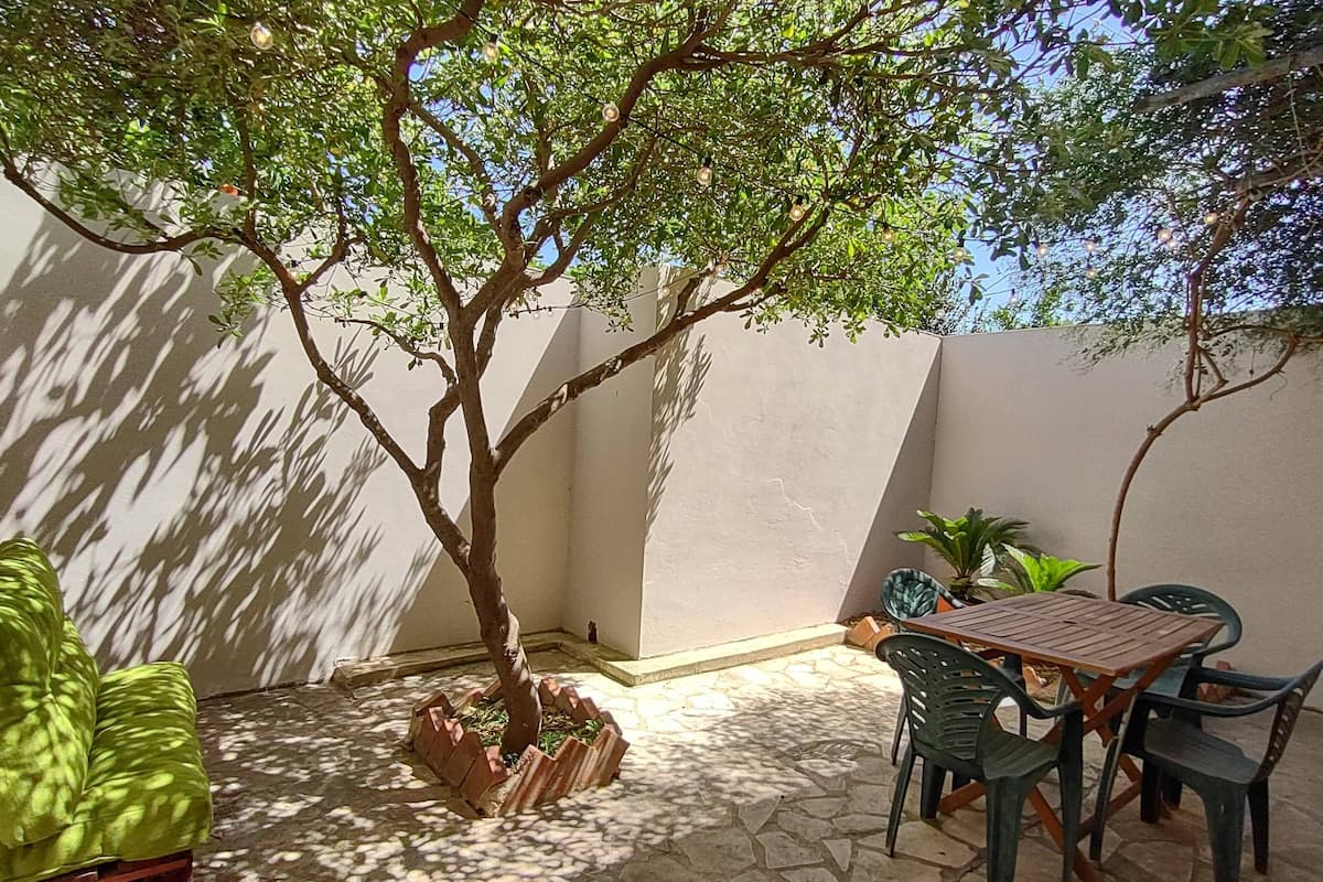 Eine Terrasse mit Tisch und Stühlen, ein kleiner Baum und ein Blumentopf.