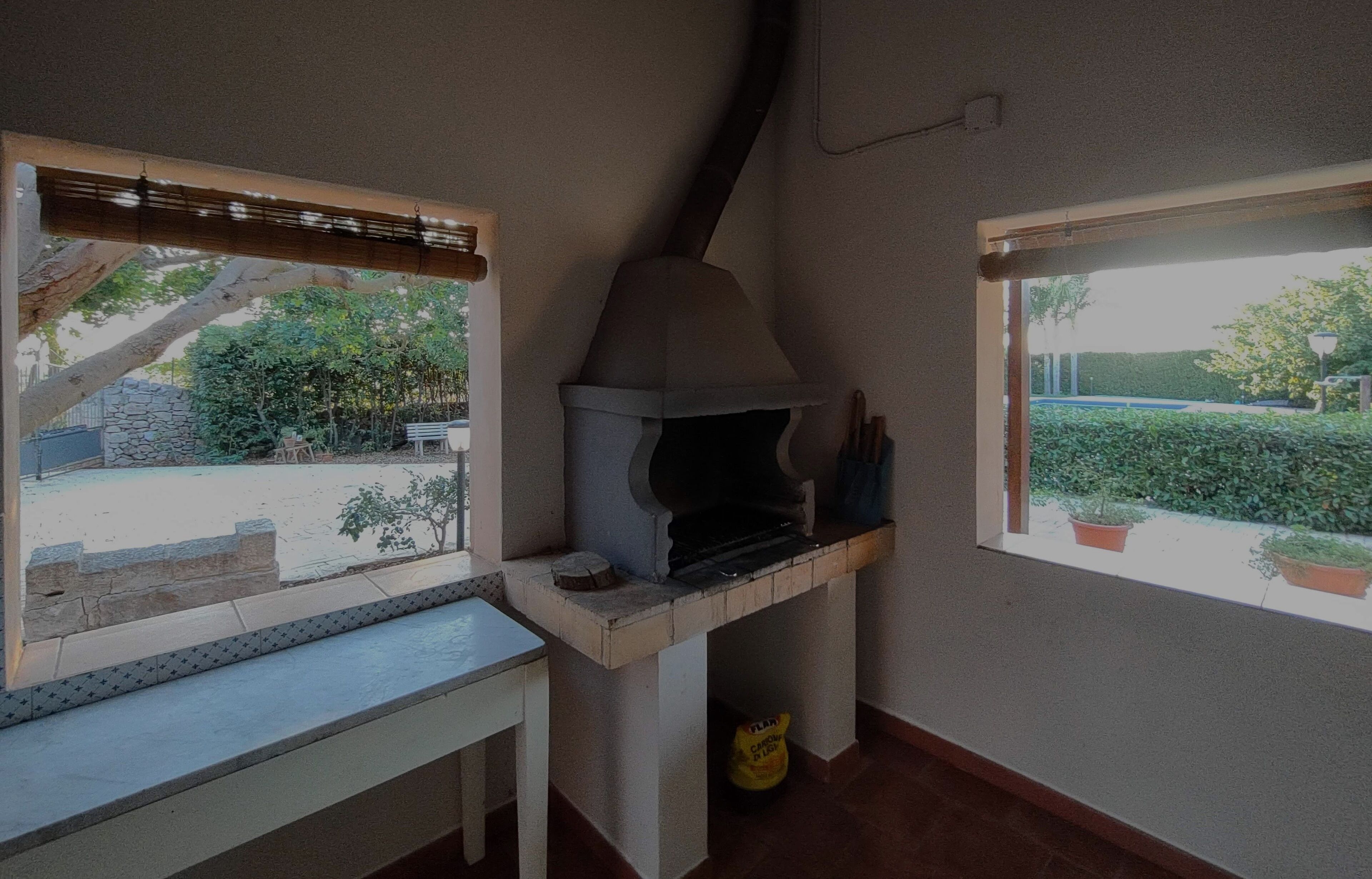 Una cuina amb forn integrat, finestra amb vista a un jardí i una taula petita.