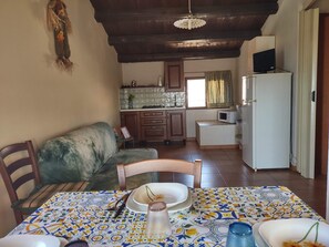 A cozy kitchen with a dining area, featuring a tiled backsplash, wooden cabinets, and a built-in microwave. - Casale Imperatore (Ragusa)