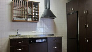 Une cuisine avec des meubles de rangement en bois foncé, un lave-vaisselle encastré et une hotte de cuisinière en acier inoxydable.
