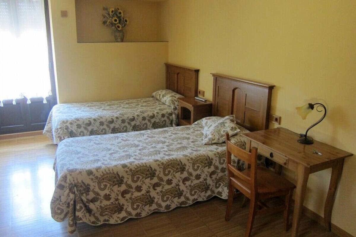 Une chambre avec deux lits, un bureau en bois et une chaise.