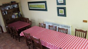 Un coin repas avec une nappe à carreaux rouges et blancs, des chaises en bois, une bibliothèque et des tableaux encadrés accrochés au mur.