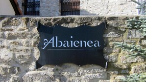 Un mur de pierres sur lequel est apposée une plaque portant l’inscription « Abaienea ».