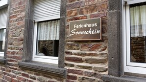 A stone building with a sign reading "Ferienhaus Sonnschein" and a window with a shutter. - Hotel Haus Sonnschein (Cochem)