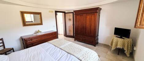 A bedroom with a bed, dresser, wardrobe, television, and a chandelier.