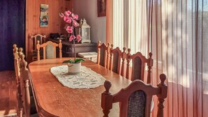 Una mesa de comedor de madera con un camino de encaje, rodeada de sillas de madera con asientos acolchados.