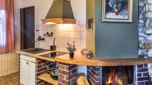 Una cocina con chimenea de ladrillo, estufa y una planta en maceta.