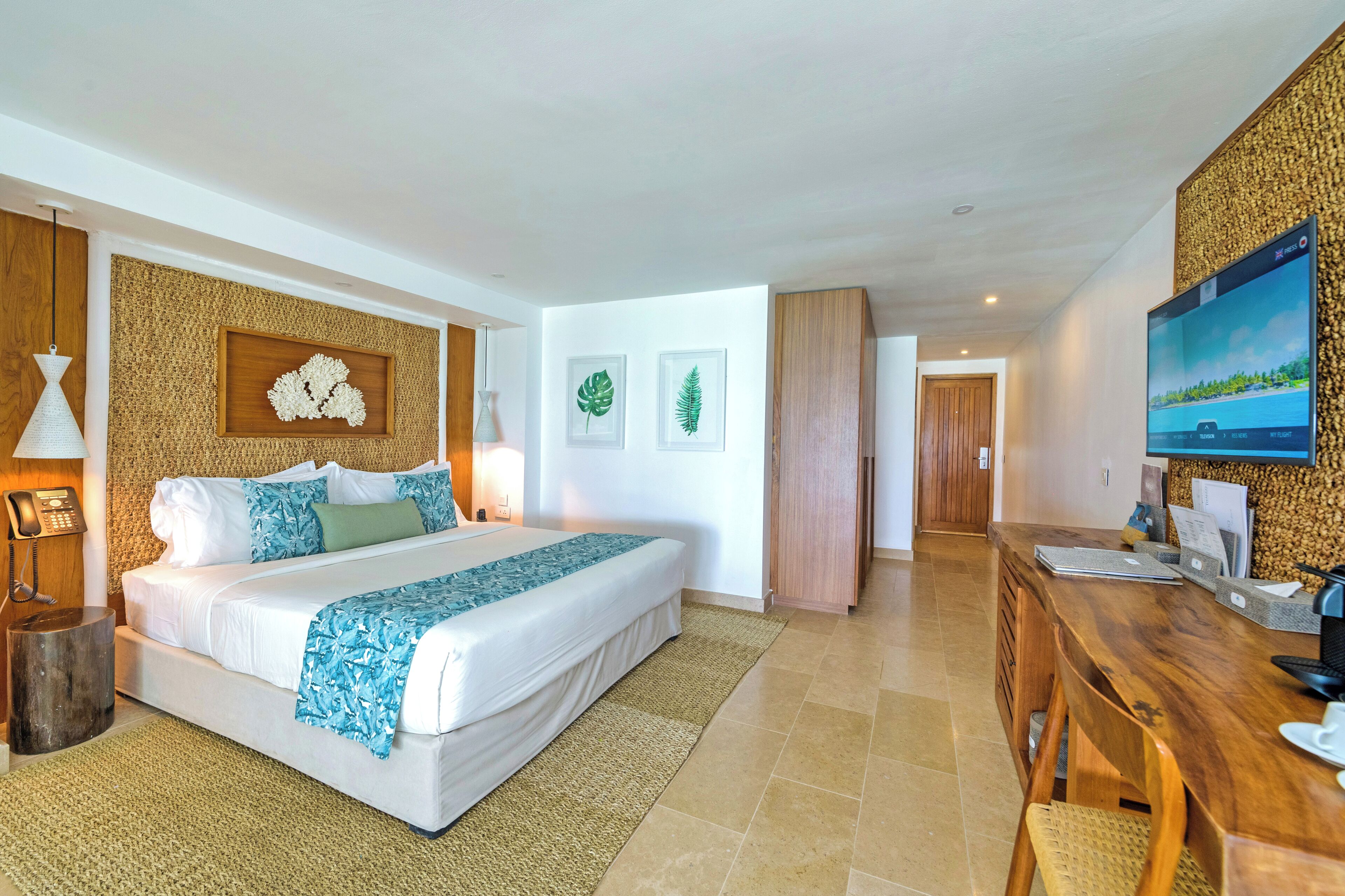 Una habitación de hotel moderna con una cama grande, un escritorio, un televisor y un panel de pared de madera.