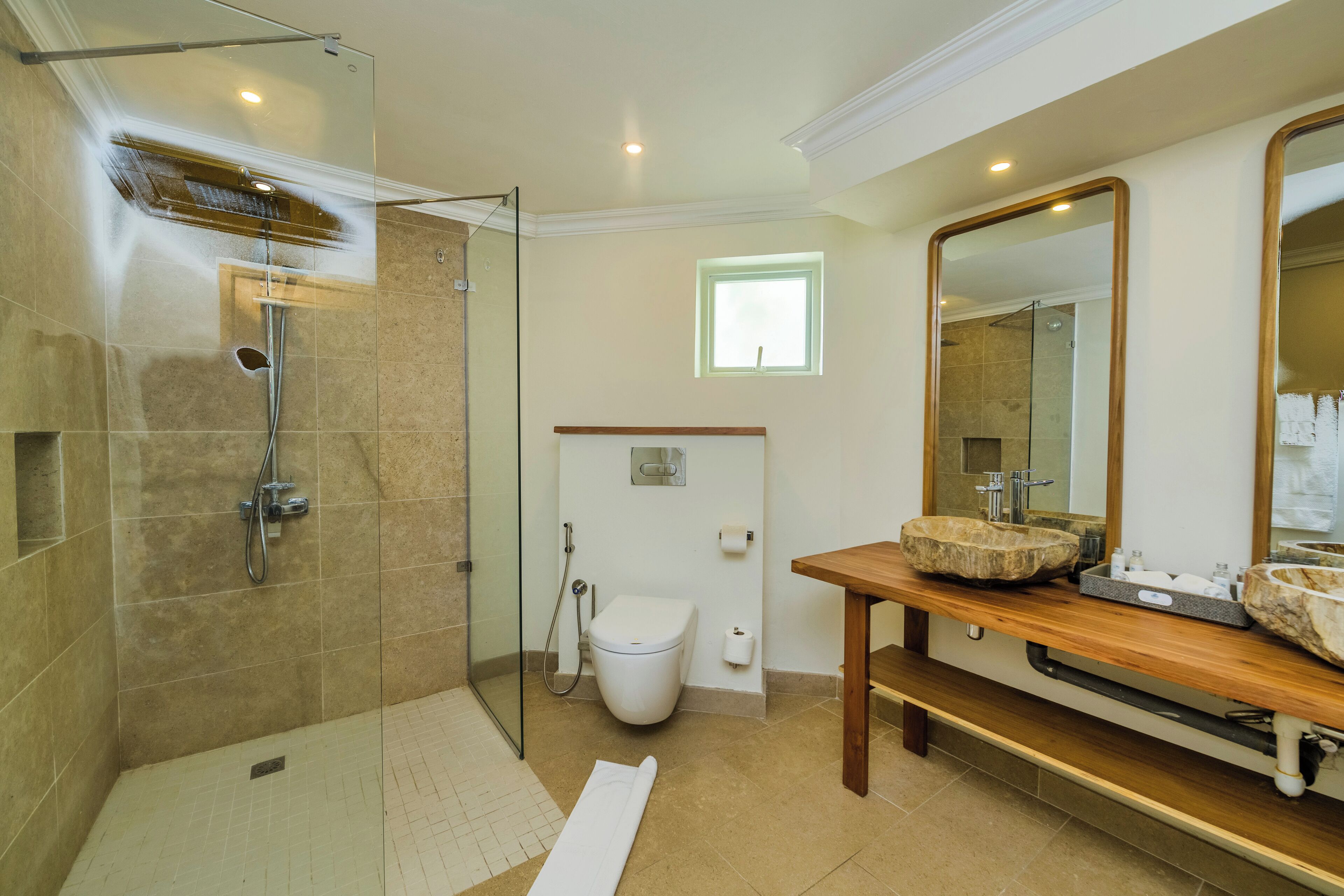Un baño moderno con ducha de vidrio, tocador de madera y un espejo grande.