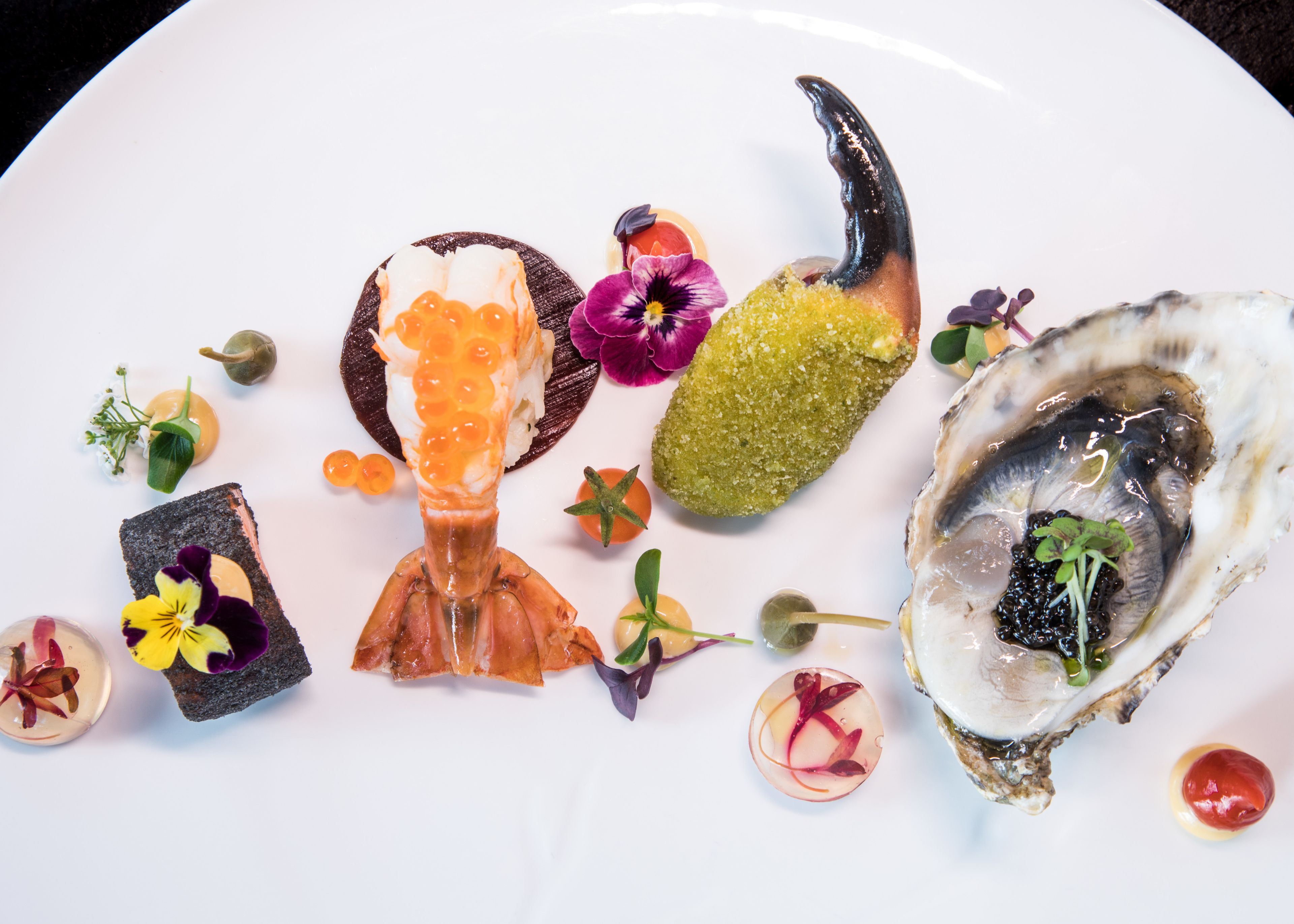 A plate with various food items including oysters, caviar, and a decorative toothpick.