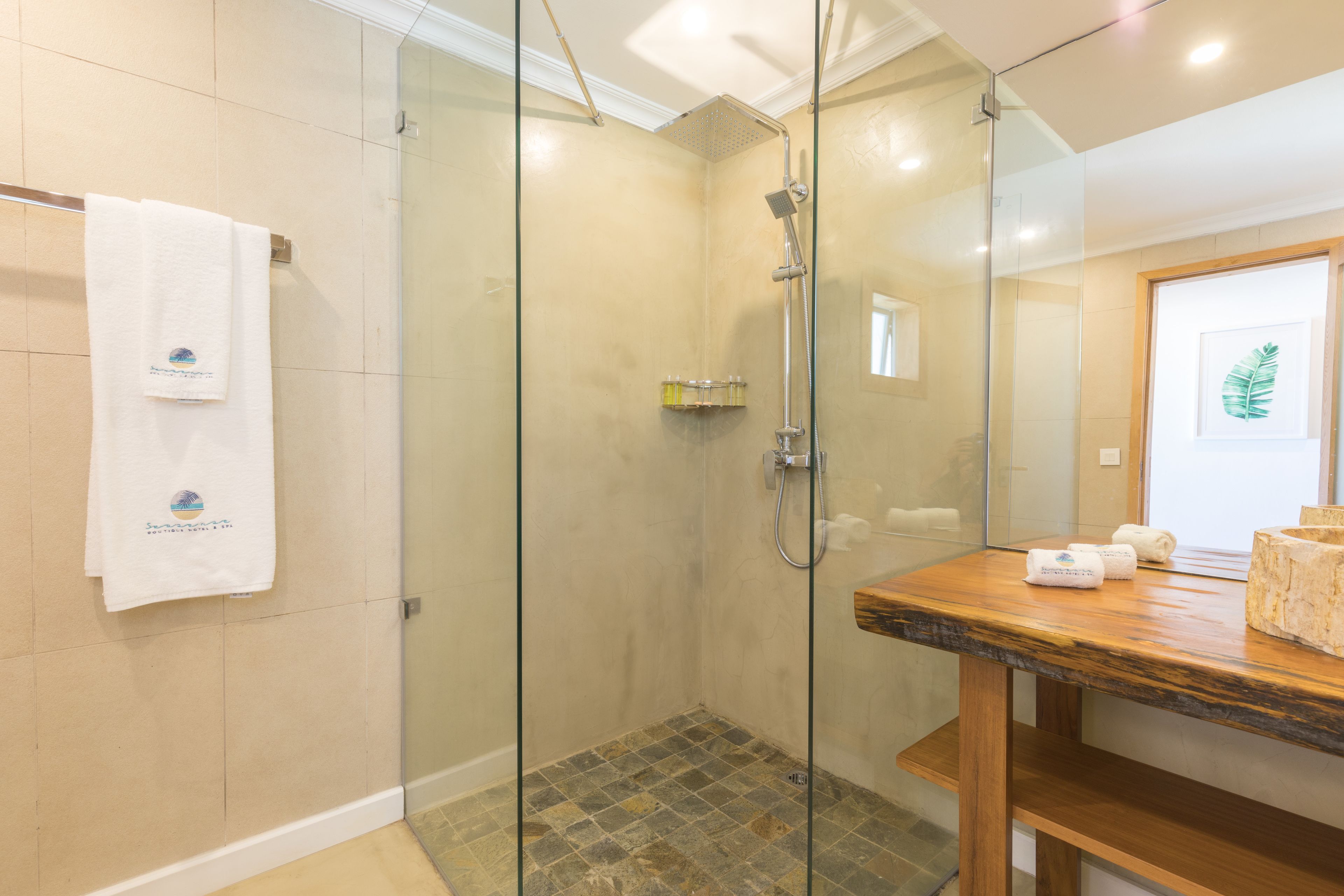 Een moderne badkamer met een douche met glazen wand, een houten wastafelmeubel en een handdoekrek met een handdoek erop.