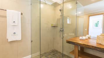 Een moderne badkamer met een douche met glazen wand, een houten wastafelmeubel en een handdoekrek met een handdoek erop.