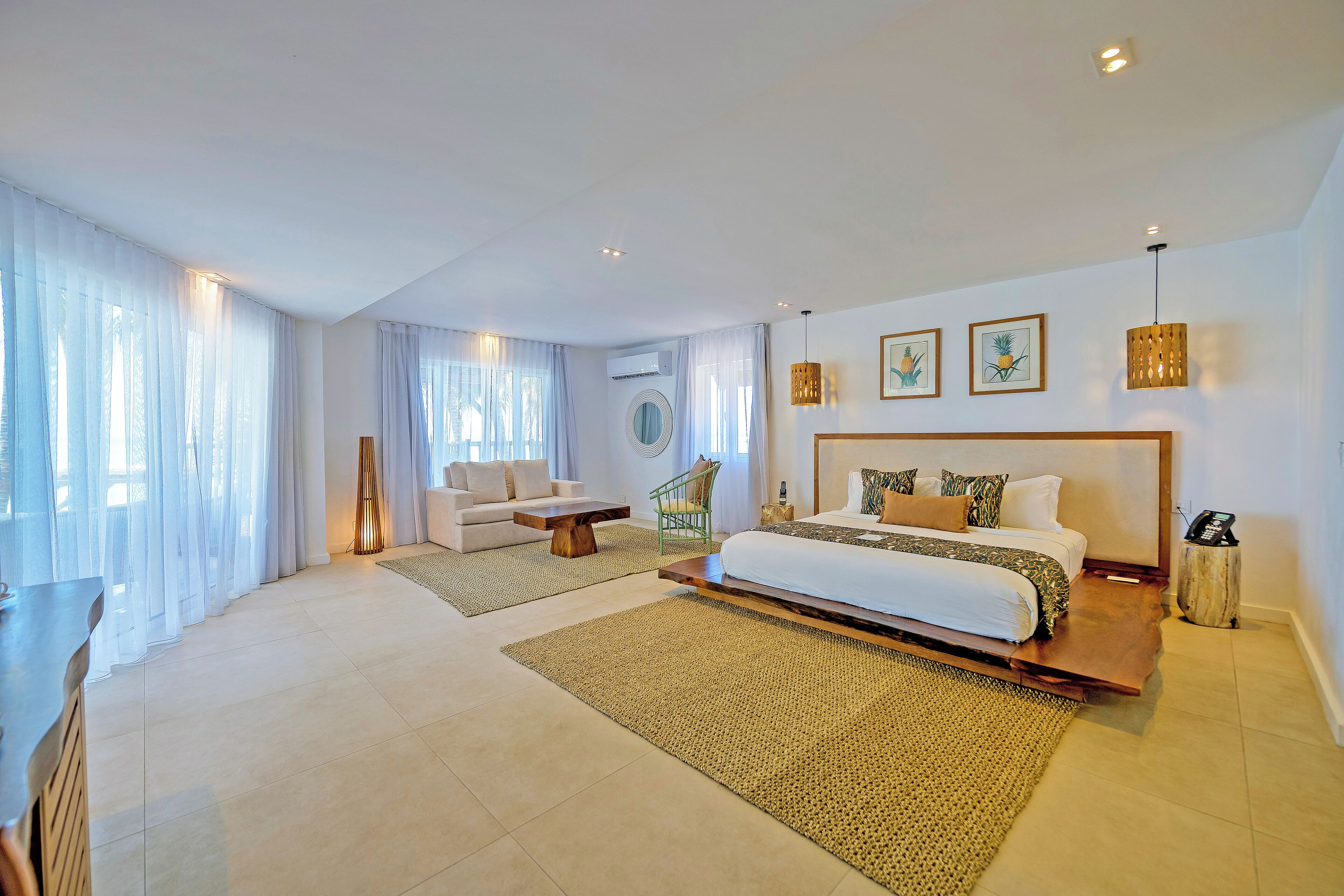 Une chambre spacieuse avec un grand lit, un coin salon avec un canapé et une table basse, et un coin repas avec une table et des chaises.