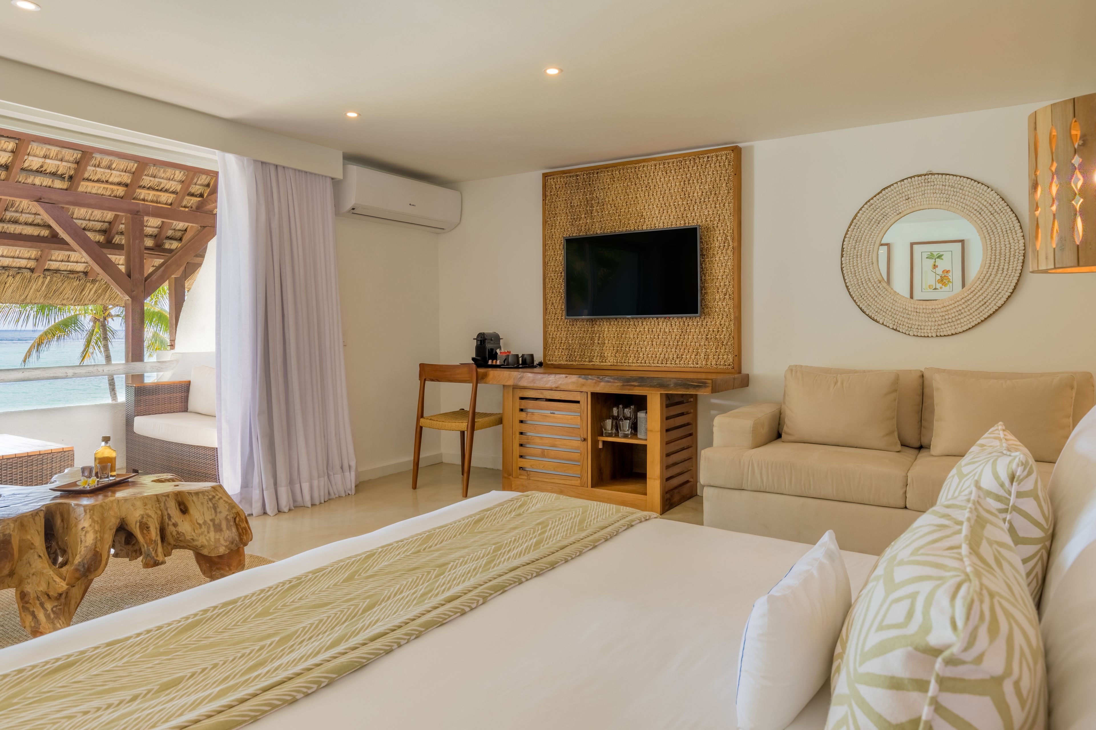 Une chambre avec un grand lit, un bureau en bois, une télévision et une vue sur l’océan.