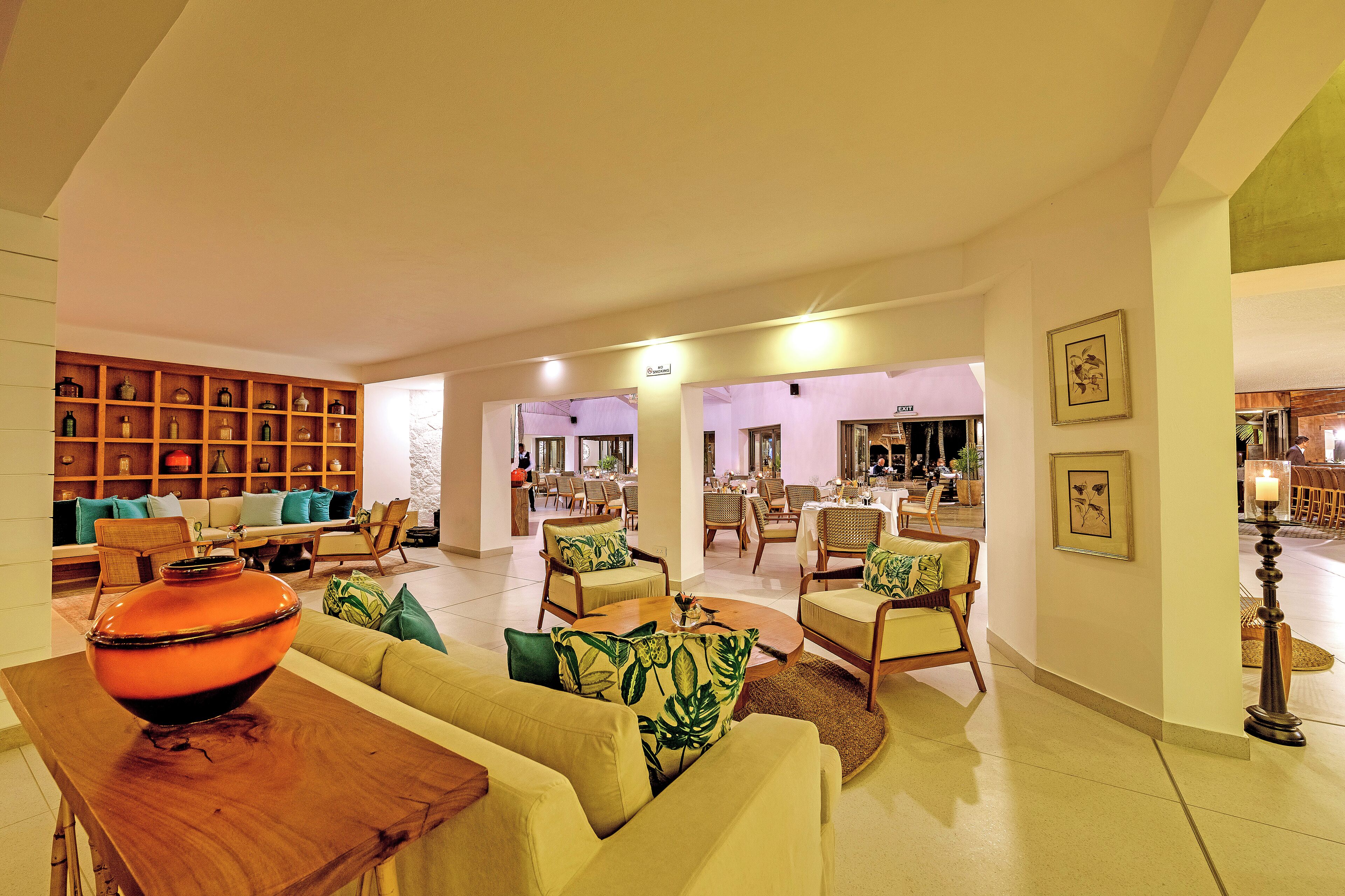 A spacious living area with a sofa, armchairs, a coffee table, and a bookshelf.
