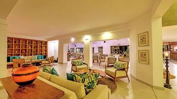 A spacious living area with a sofa, armchairs, a coffee table, and a bookshelf.