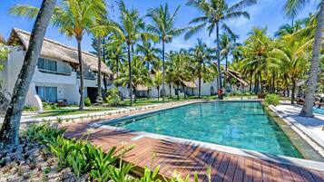 A swimming pool surrounded by palm trees and a wooden deck.