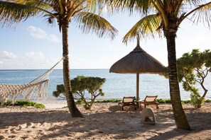 A beach with a hammock, a thatched umbrella, and two lounge chairs. - Seasense Boutique Hotel & Spa (Belle Mare)