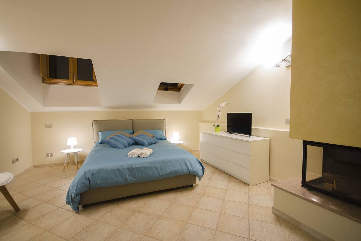 A bedroom with a bed, a TV, a dresser, and a small table.