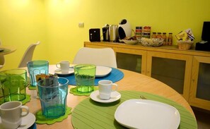 Una mesa de comedor con individuales verdes, platos blancos y diferentes copas.