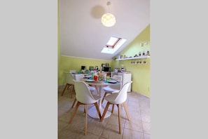 Un comedor con una mesa redonda, sillas blancas, una lámpara de techo y un tragaluz.