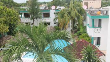 A view of a hotel with multiple buildings, including a pool area surrounded by palm trees and other greenery.