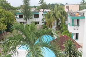 A view of a hotel with multiple buildings, including a pool area surrounded by palm trees and other greenery.
