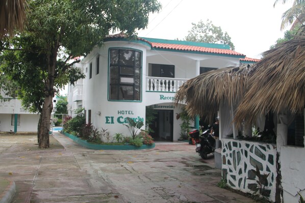 A hotel named "Hotel El Camino" with a curved facade, a balcony, and a thatched roof structure.