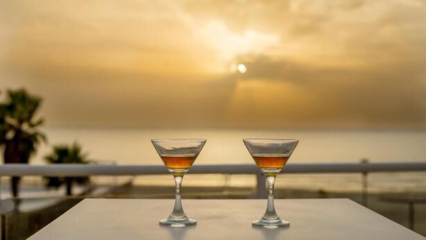 Zwei Martini-Gläser auf einem Tisch mit Blick auf einen Sonnenuntergang.